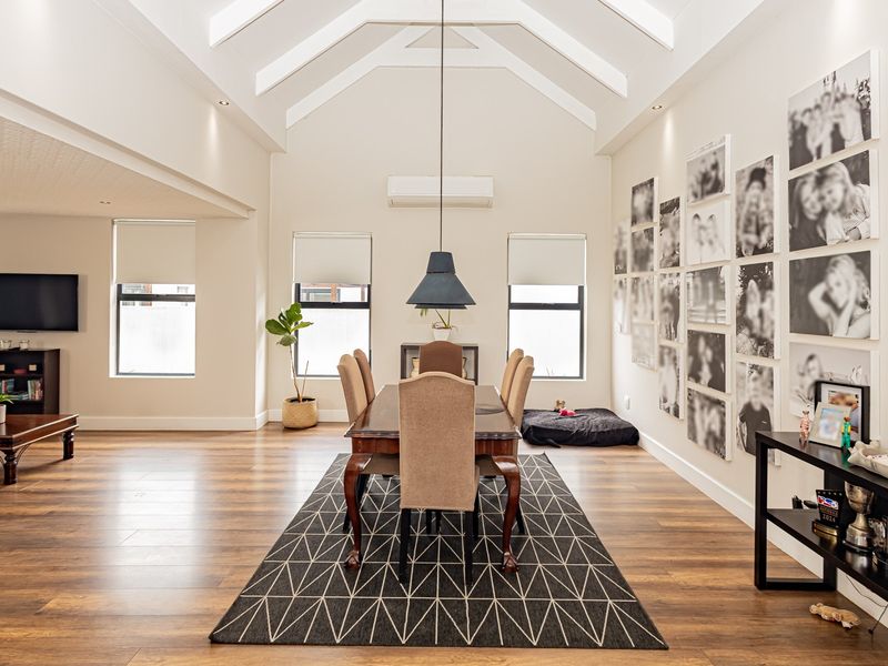 Spacious open-plan living and dining area featuring high vaulted ceilings, modern laminate flooring, and recessed lighting, creating a bright and airy atmosphere.