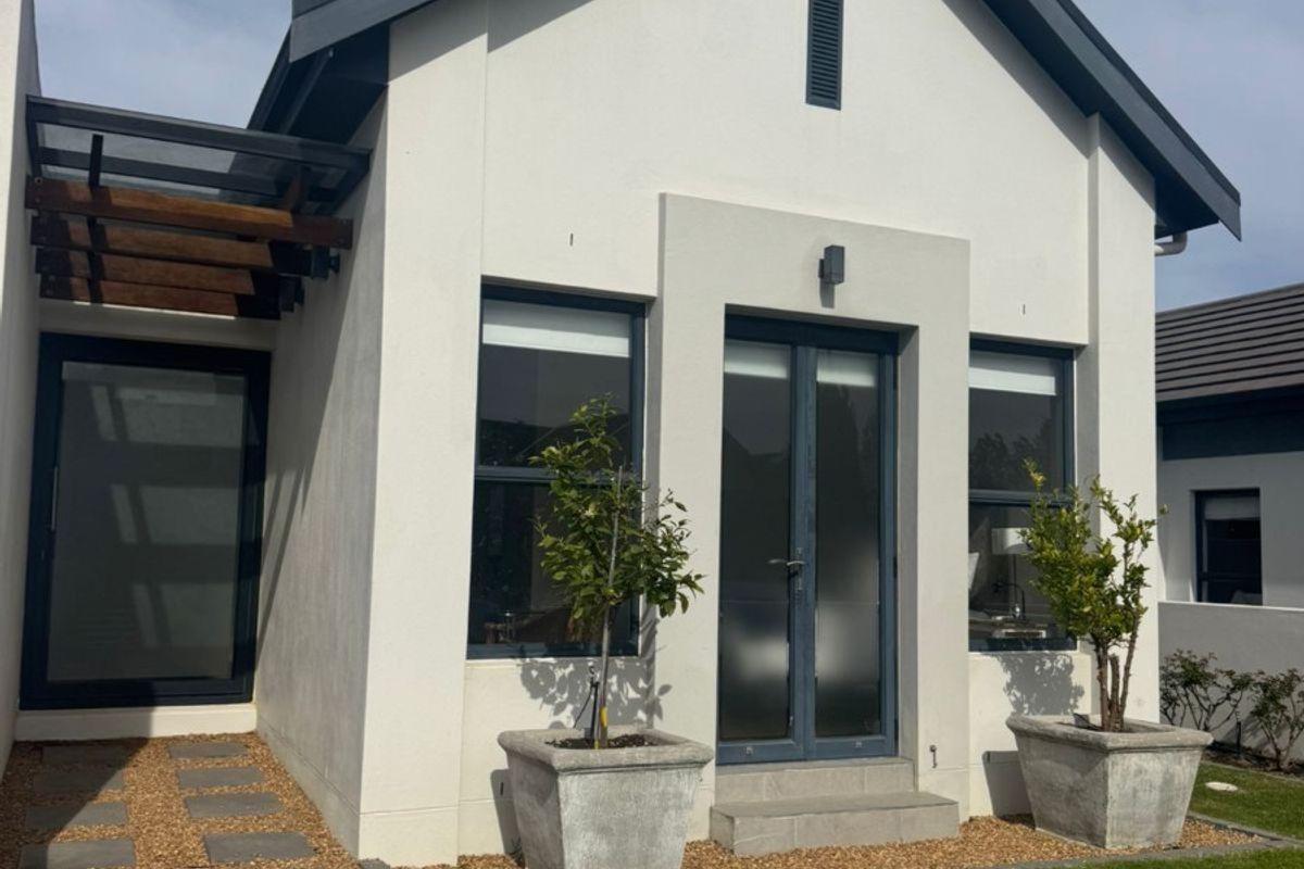 A modern rear exterior view featuring a clean white facade, dark window frames, a timber pergola, and a well-maintained garden with a paved walkway.