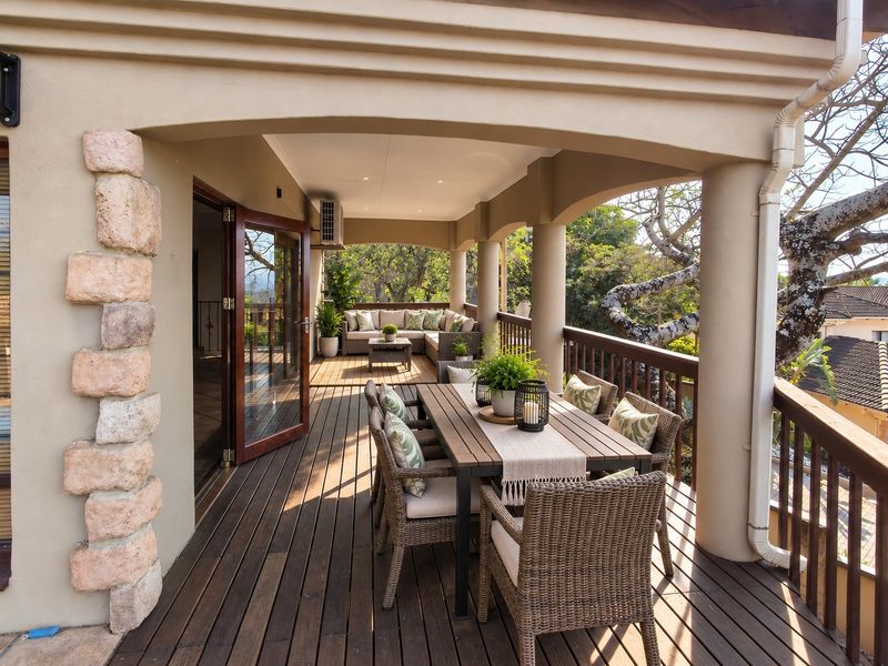 Spacious covered balcony featuring timber decking, stone accents, and bi-fold doors, providing an ideal outdoor entertainment area with elevated views.