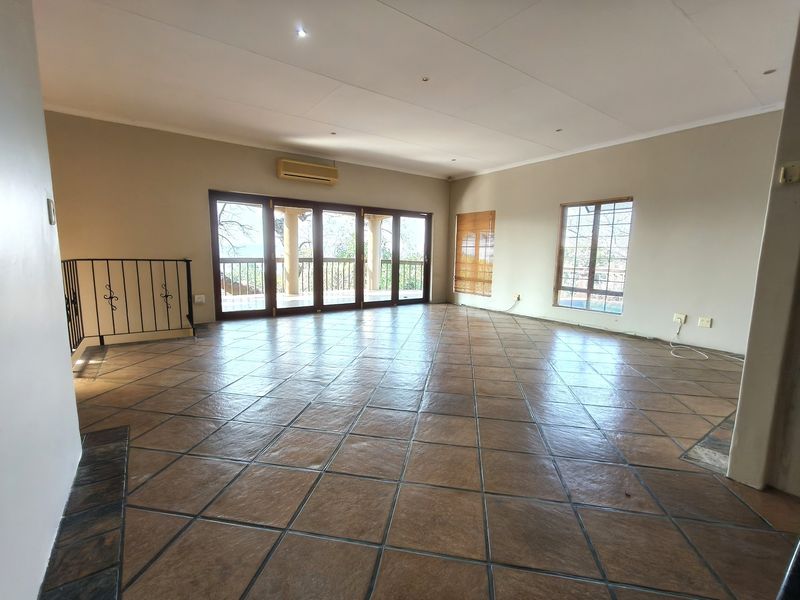 Spacious, empty living area featuring tiled floors, recessed lighting, an air conditioning unit, and large sliding doors leading to an outdoor space.