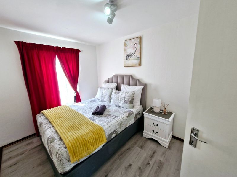 A well-maintained bedroom featuring light-toned laminate flooring and neutral wall finishes, providing a clean and functional living space.
