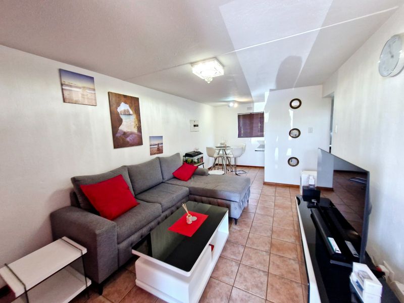 Open-plan living and dining area featuring tiled flooring and neutral walls, providing a functional space for relaxation and meals.