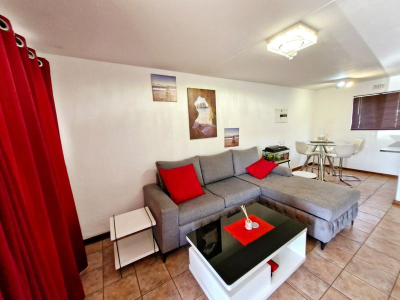 Open plan living and dining area featuring tiled flooring, neutral walls, and natural light through venetian blinds.