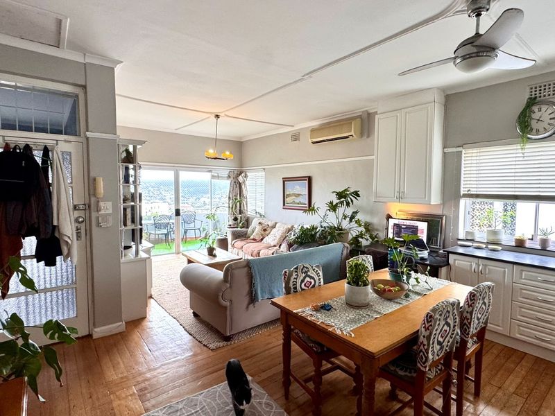 Open-plan living and dining area featuring hardwood floors, a ceiling fan, split-system air conditioning, and direct access to a balcony with scenic views.
