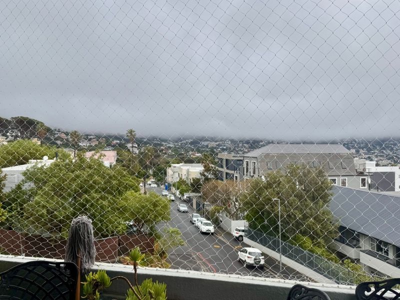 An elevated view overlooking the surrounding neighbourhood and street, captured from a balcony protected by safety netting.