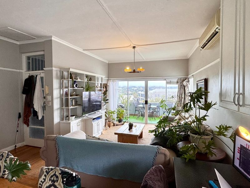 Open-plan living area featuring hardwood floors, built-in cabinetry, and sliding glass doors leading to a balcony with scenic views.