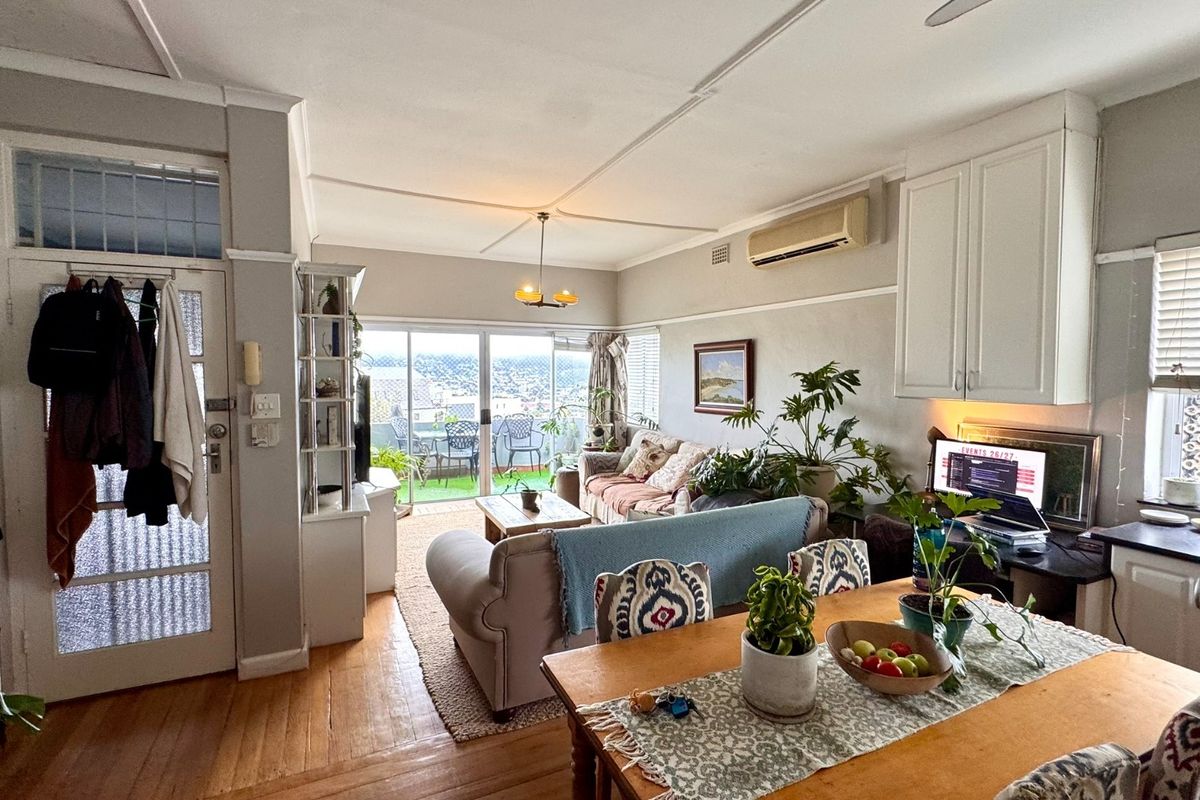 Open-plan living and dining area featuring hardwood floors, built-in cabinetry, and sliding glass doors leading to a balcony with city views.
