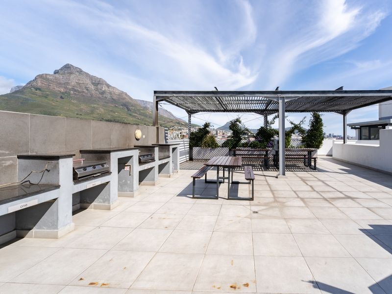 Spacious rooftop terrace featuring built-in braai stations, a shaded pergola, and panoramic mountain views, perfect for outdoor entertaining.