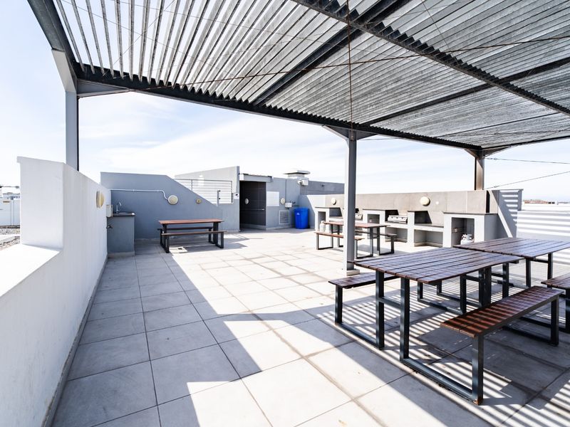 Spacious rooftop patio featuring a metal pergola, built-in braai area, and outdoor sink, providing an ideal space for outdoor entertaining.