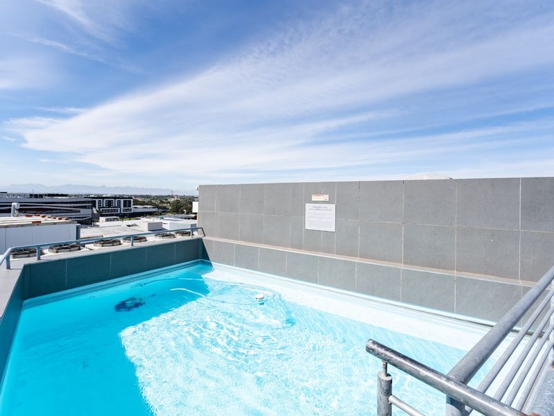 Rooftop swimming pool featuring tiled surrounds and metal safety railings with expansive city views.