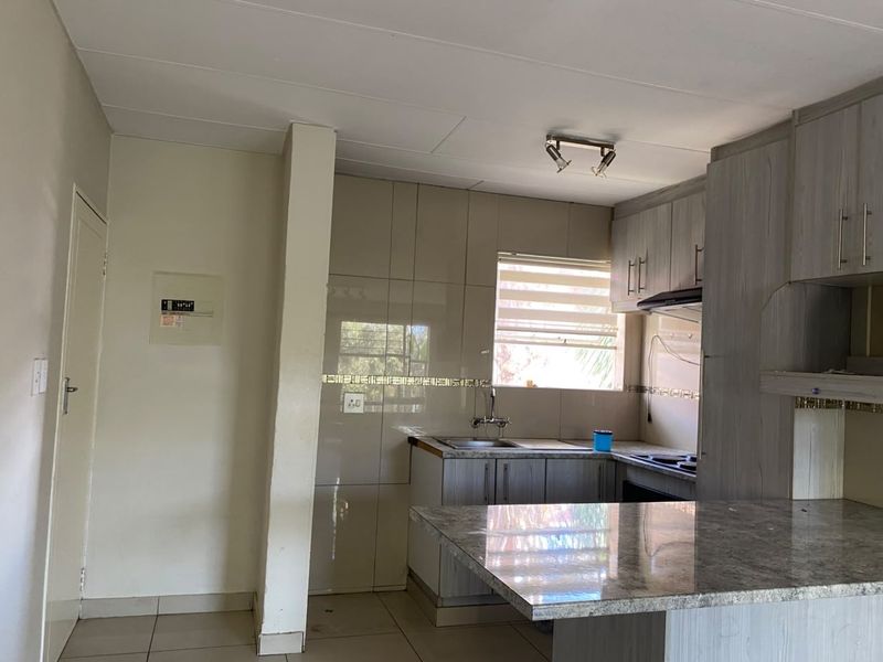 A functional kitchen featuring built-in cabinetry, granite countertops, a tiled backsplash, and a breakfast nook area.