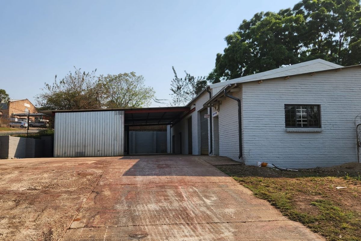 Front exterior view of a commercial property featuring a concrete driveway, painted brick facade, and metal roller shutter access.