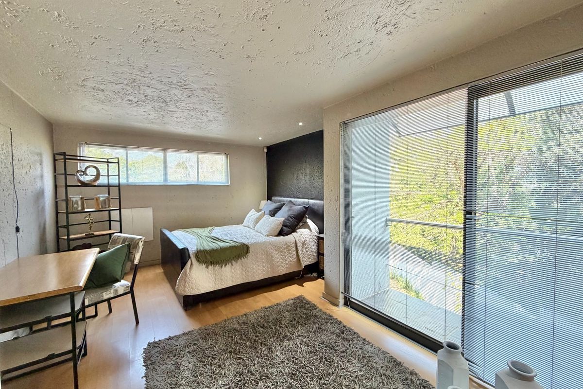 Spacious bedroom featuring laminate flooring, textured ceiling, and large sliding glass doors with access to an outdoor balcony area.