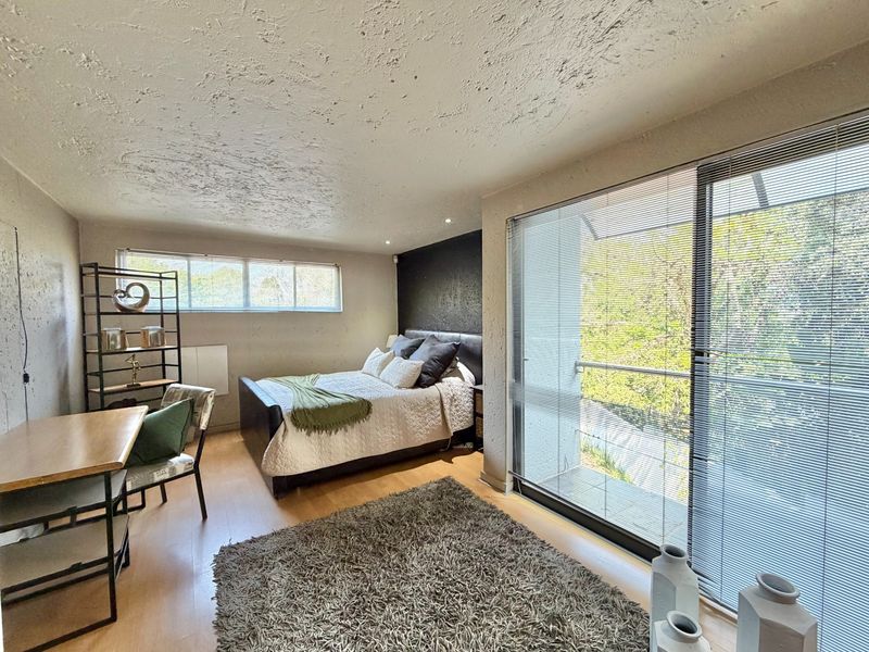 Spacious bedroom featuring laminate flooring, textured ceiling, and large sliding glass doors with access to an outdoor balcony area.