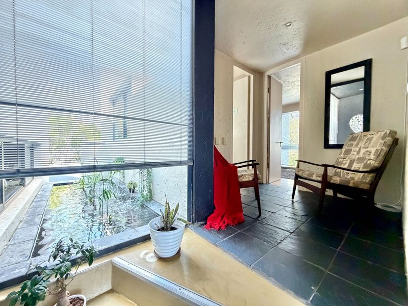 A covered patio area featuring slate tile flooring and a built-in water feature, providing a unique indoor-outdoor transition space.