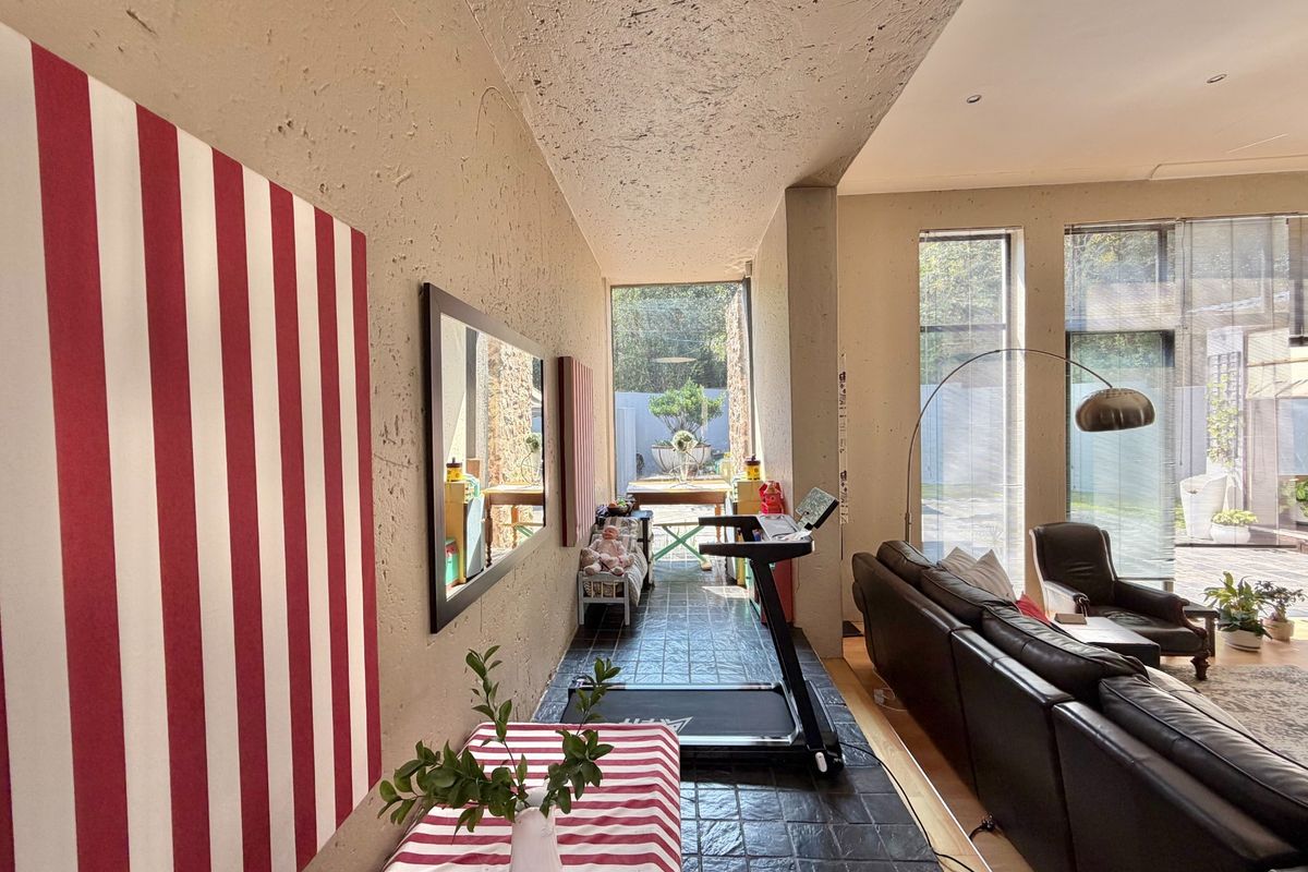 Spacious living area featuring exposed concrete ceilings, large windows providing natural light, and tiled flooring, offering a unique industrial-style aesthetic.