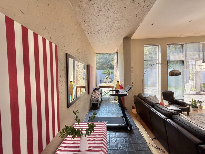 Spacious living area featuring exposed concrete ceilings, large windows providing natural light, and tiled flooring, offering a unique industrial-style aesthetic.