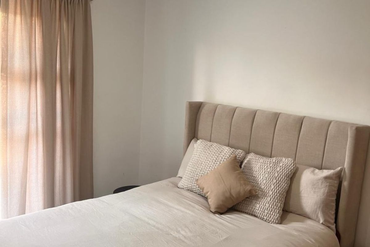 A well-maintained bedroom featuring neutral tones, tiled flooring, and a ceiling light fixture.