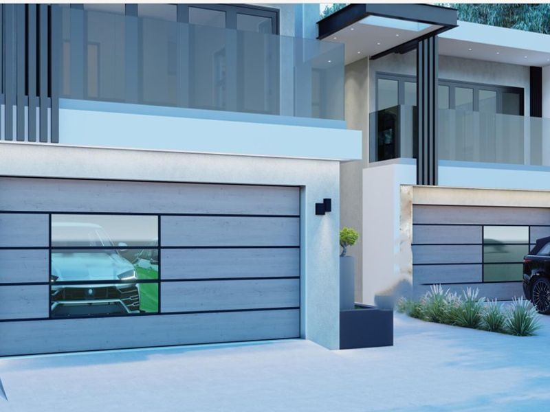 Modern double-story residential facade featuring contemporary garage doors, glass balcony railings, and clean architectural lines.