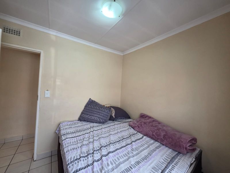 A simple bedroom featuring neutral wall finishes, coving, and a flush mount ceiling light fixture.