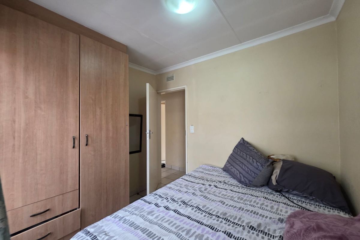 A functional bedroom featuring a built-in wooden wardrobe and neutral wall finishes, providing a practical and comfortable sleeping space.
