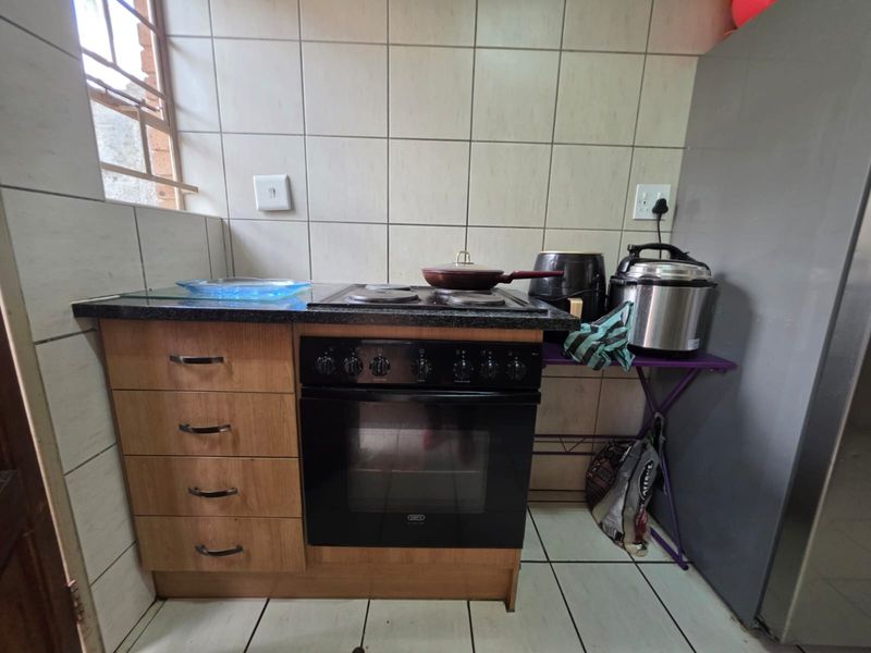 A compact kitchen area featuring a built-in oven, electric hob, laminate cabinetry, and tiled backsplash.