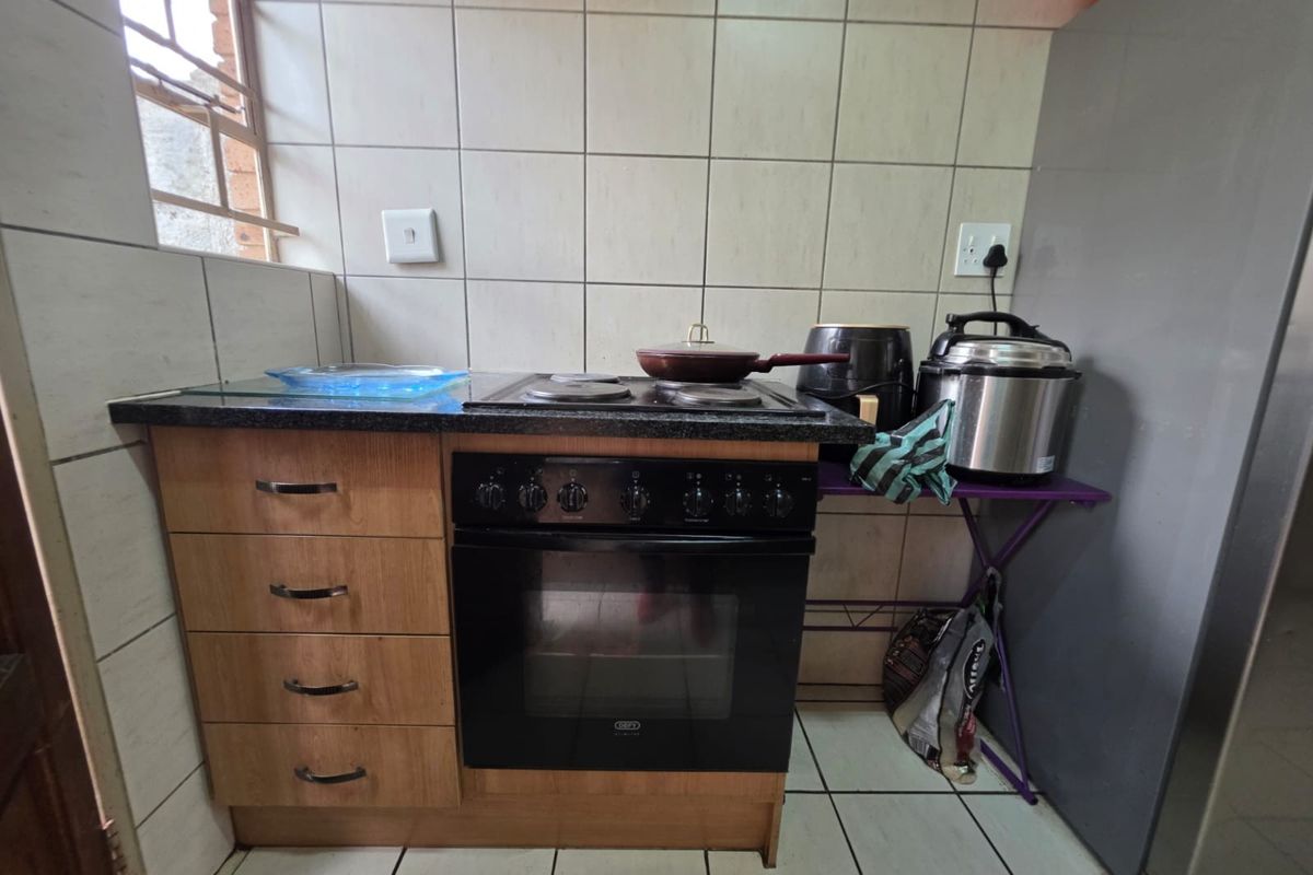 A compact kitchen area featuring a built-in oven, electric hob, laminate cabinetry, and tiled backsplash.