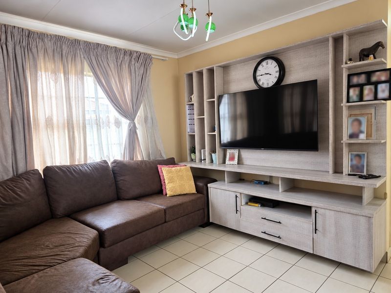 A comfortable living room featuring a large built-in media unit with shelving and tiled flooring, providing a functional and organized entertainment space.