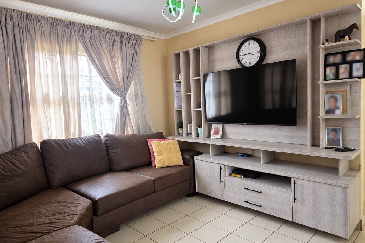 A comfortable living room featuring a large built-in media unit with shelving and tiled flooring, providing a functional and organized entertainment space.