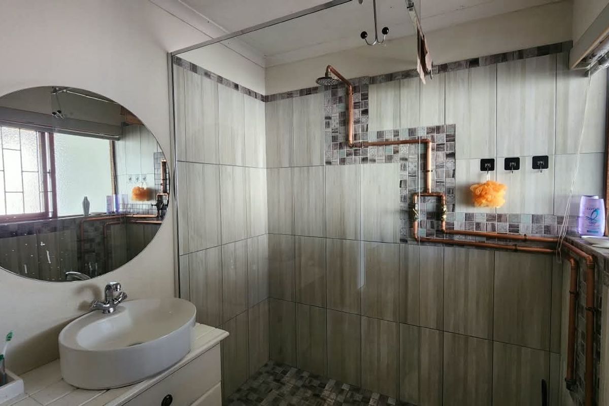 Bathroom featuring a vessel sink vanity, tiled shower enclosure, and exposed copper plumbing fixtures.