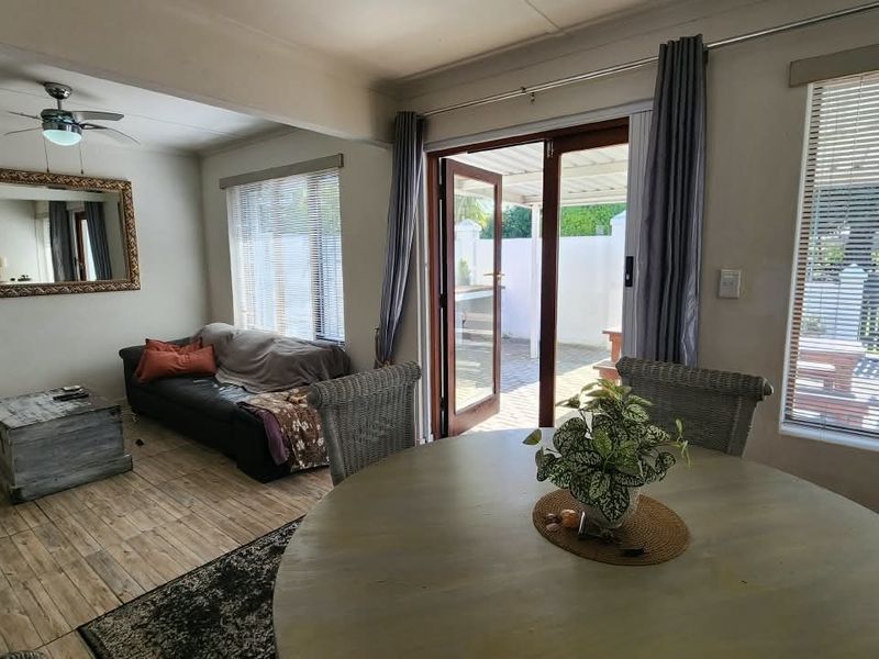 Open-plan living and dining area featuring tiled flooring, a ceiling fan, and direct access to an outdoor patio through double glass doors.