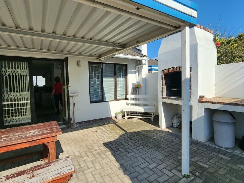 Covered outdoor patio featuring a built-in braai area and paved flooring, providing a functional space for outdoor entertaining.