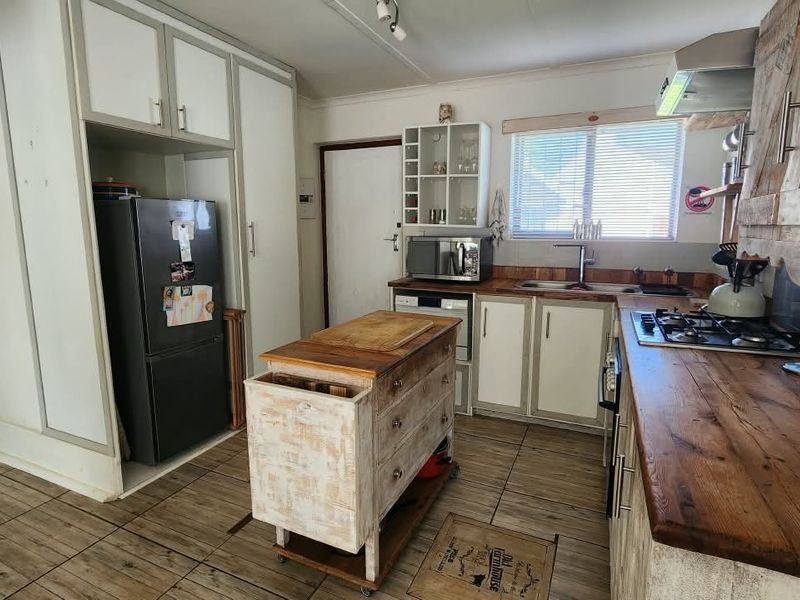 A rustic-style kitchen featuring wooden countertops, a gas hob, extractor fan, and ample built-in cabinetry with tiled flooring throughout.