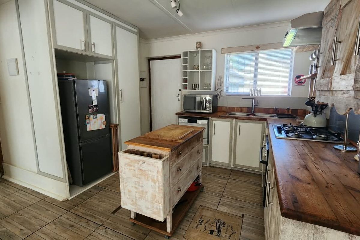 A rustic-style kitchen featuring wooden countertops, a gas hob, extractor fan, and ample built-in cabinetry with tiled flooring throughout.