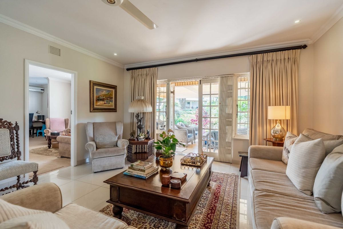 A bright and inviting living room featuring tiled flooring, recessed lighting, and classic french doors that open onto a patio area.