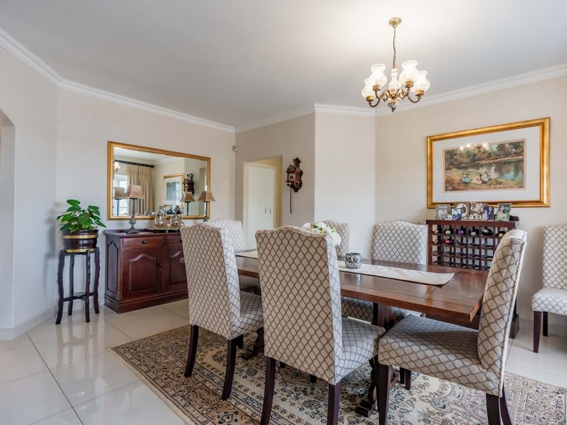 A well-maintained dining room featuring polished tiled flooring, coved ceilings, and a classic chandelier, providing a bright and inviting space for formal meals.