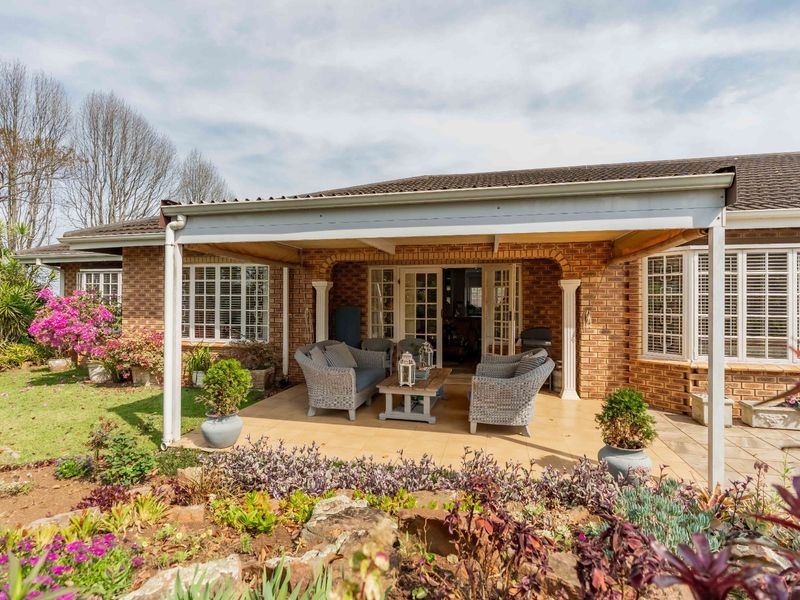 A well-maintained covered patio area featuring brick exterior walls, tiled flooring, and direct access to the interior through classic french doors.