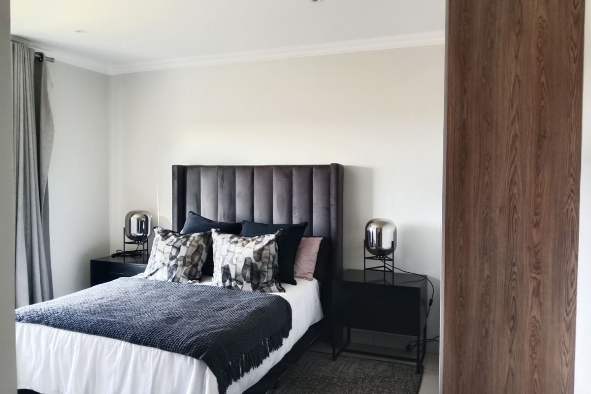 A well-maintained bedroom featuring recessed downlighting, decorative coving, and a large built-in wooden wardrobe.