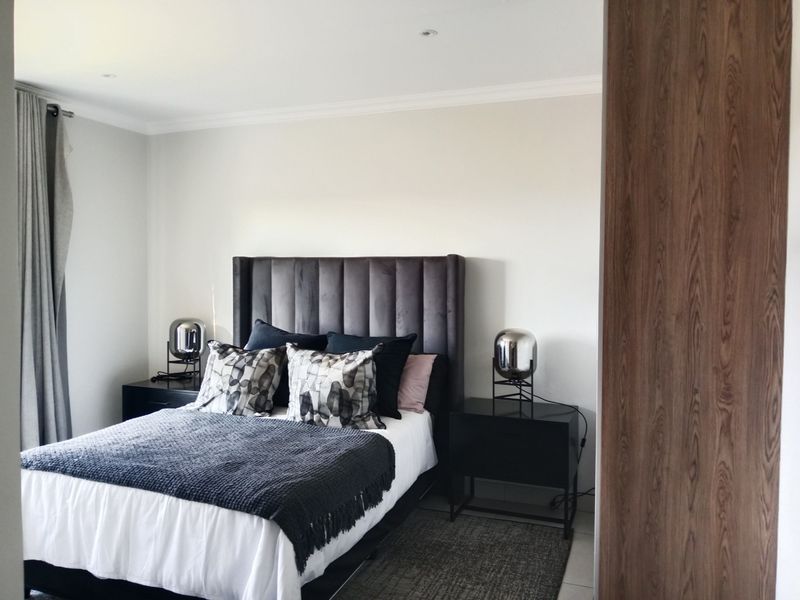 A well-maintained bedroom featuring recessed downlighting, decorative coving, and a large built-in wooden wardrobe.