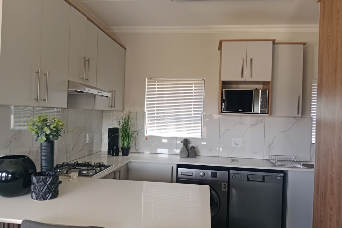Modern kitchen featuring light-toned cabinetry, quartz countertops, marble-look splashbacks, and integrated appliances including a gas hob and dishwasher.