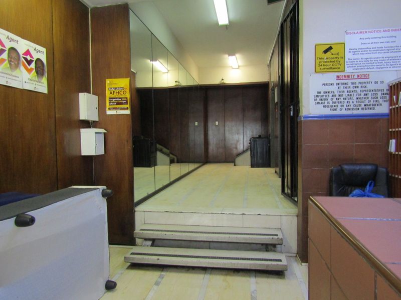 A functional apartment building entrance lobby featuring tiled flooring, wood paneling, and a large mirrored wall section.