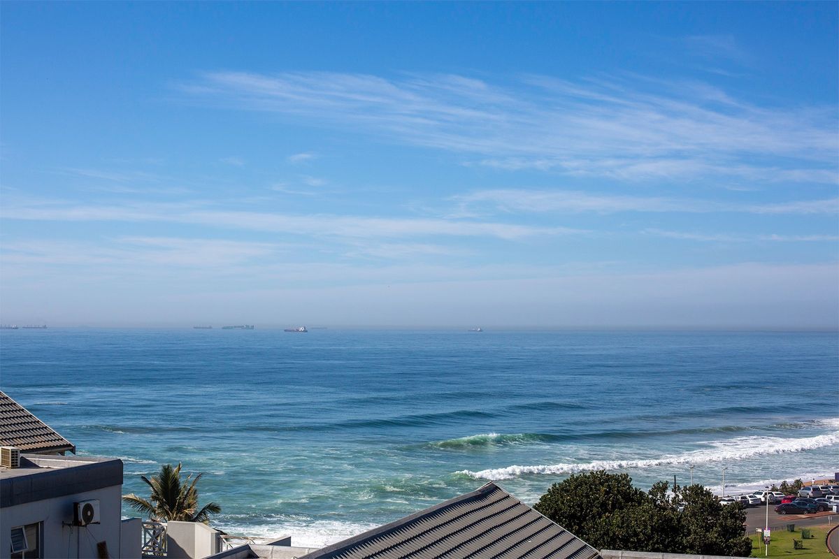 A clear, elevated ocean view showcasing the coastline, horizon, and surrounding residential rooftops.