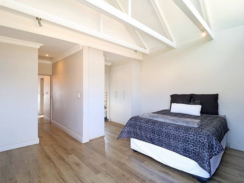 Spacious bedroom featuring high vaulted ceilings with exposed beams, laminate flooring, and convenient built-in storage cupboards.