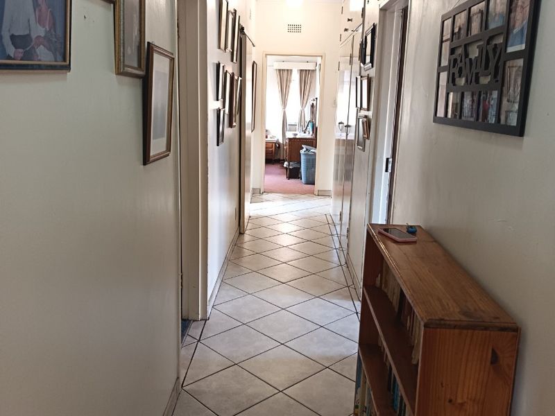 A functional hallway featuring tiled flooring and built-in storage cupboards, providing access to various rooms within the home.