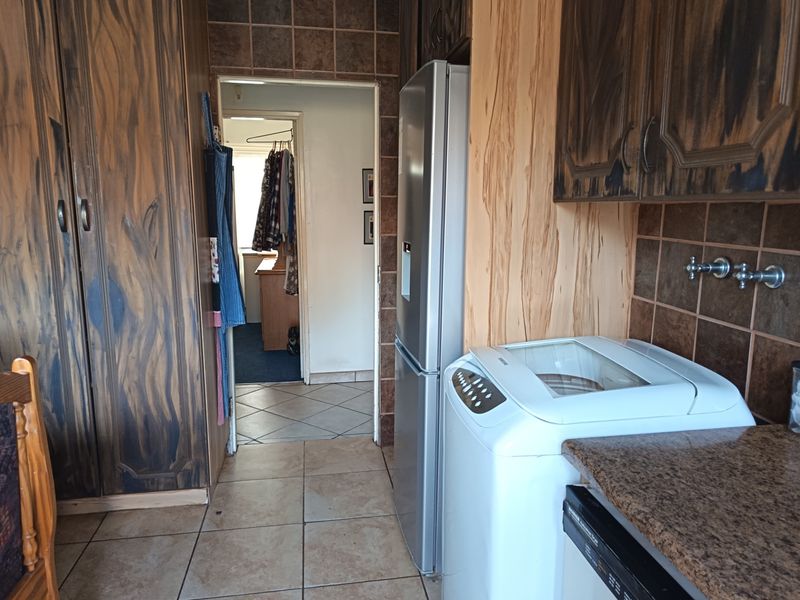 A functional scullery area featuring built-in cabinetry, tiled splashbacks, and dedicated plumbing connections for laundry appliances.