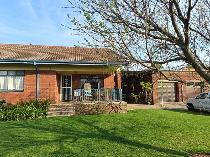 A single-story brick house featuring a covered front porch, tiled roof, attached garage, and a well-maintained front lawn.