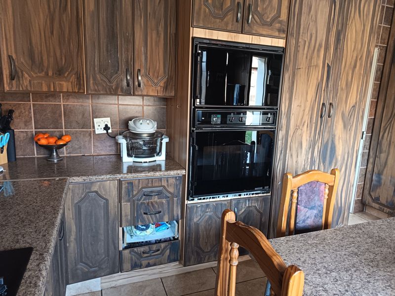 Kitchen featuring dark wood-grain cabinetry, granite countertops, and a built-in double oven with a tiled backsplash and floor.