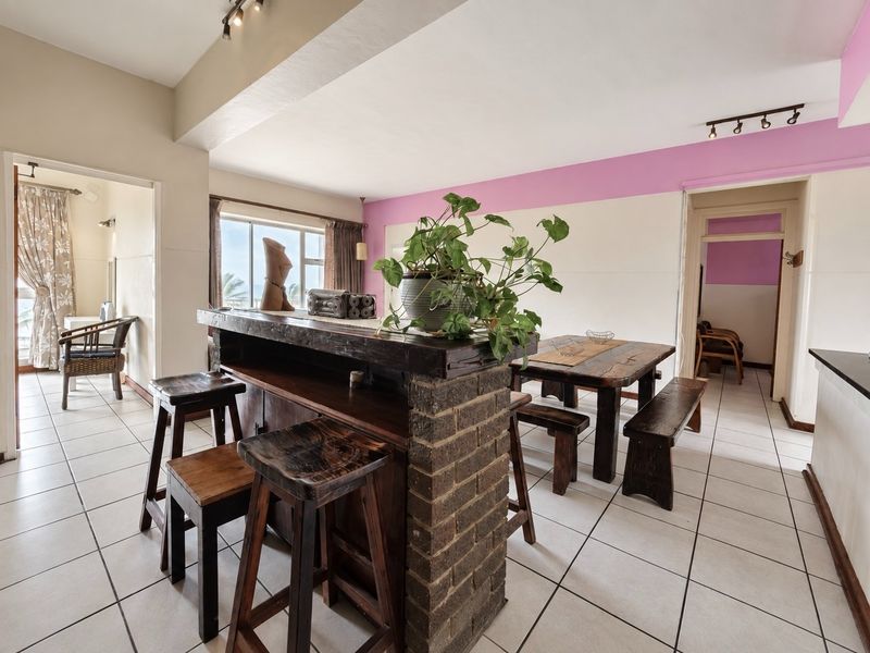 Open plan living and dining area featuring a brick breakfast bar, ceramic tiled flooring, and neutral walls with decorative accents.