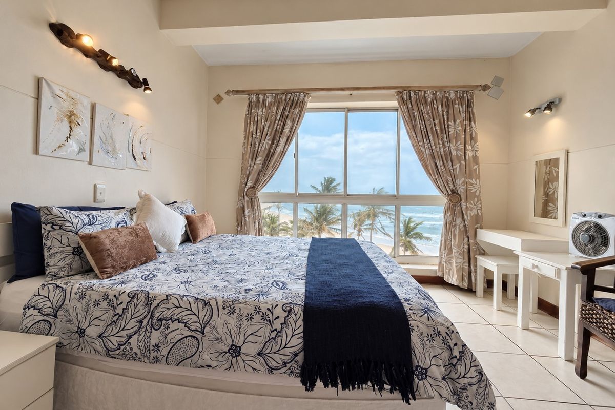 A bright bedroom featuring tiled flooring and a large sliding window offering scenic ocean views.