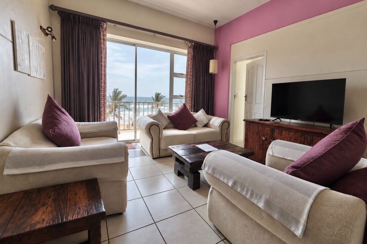 A comfortable living room featuring tiled floors and a large sliding glass door that opens onto a balcony with ocean views.